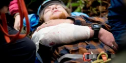 Personne blessée sur civière en forêt.
