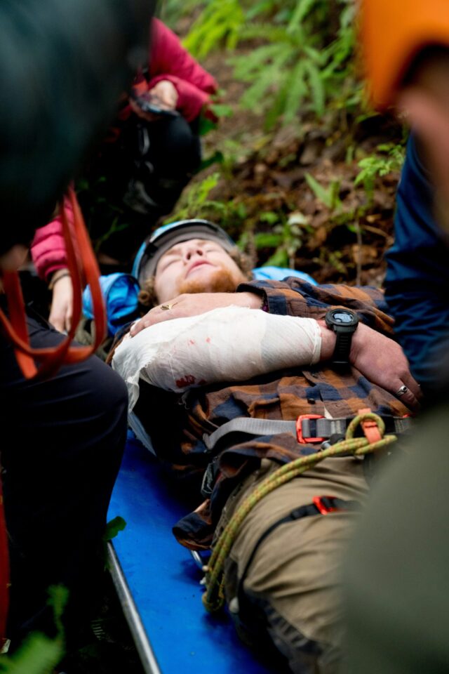 Personne blessée sur civière en forêt.