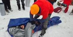 Personne emmaillotée dans une bâche sur neige.